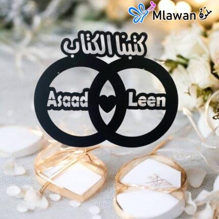 Black wooden plaque with Arabic "كتبنا الكتاب" and couple names